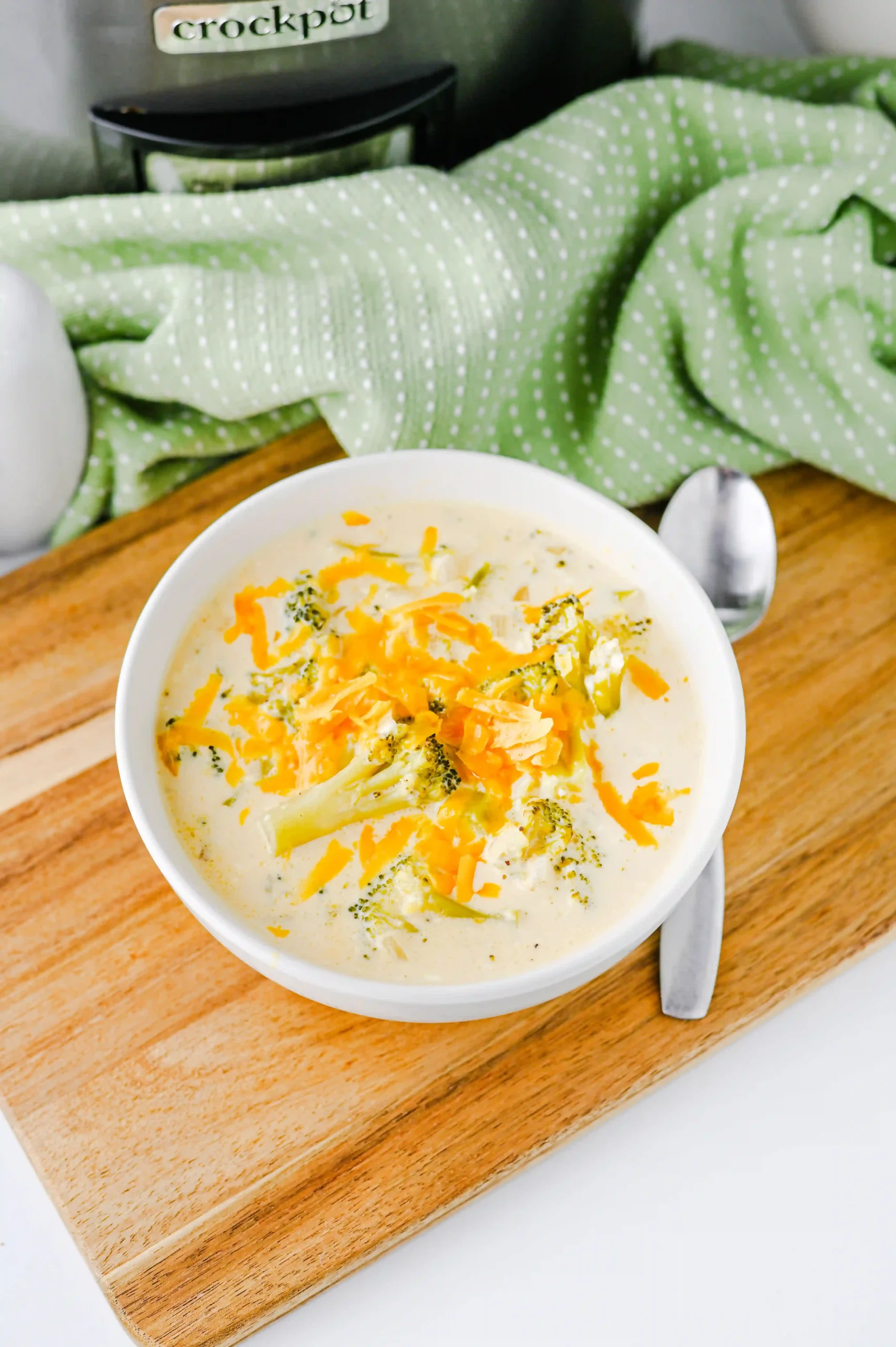 Slow Cooker Broccoli Cheddar Soup with cheese in a white bowl on a wooden board