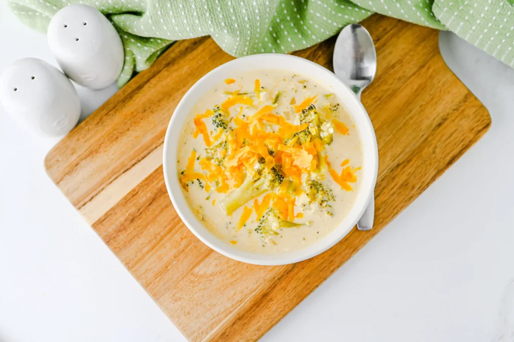 Slow Cooker Broccoli Cheddar Soup with cheese in a white bowl on a wooden board