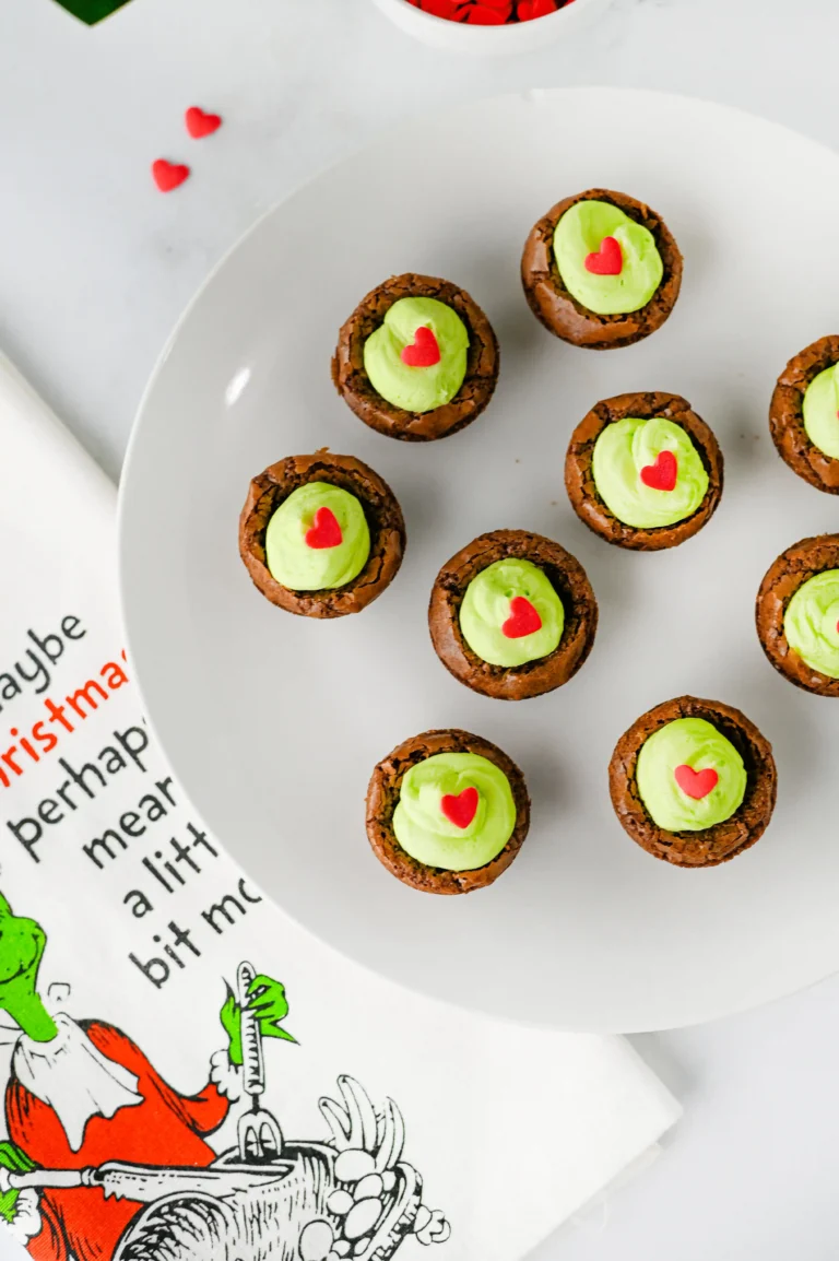 brownie bites with green frosting and a heart sprinkle on a white plate