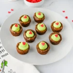 brownie bites with green frosting and a heart sprinkle on a white plate