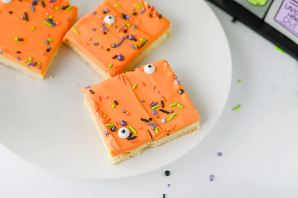 Halloween Sugar Cookie Bars with orange icing and halloween sprinkles