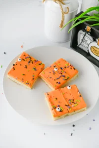 Halloween Sugar Cookie Bars with orange icing and halloween sprinkles