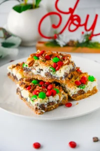 Christmas 7 Layer Bars with green and red m&ms on top on a white plate