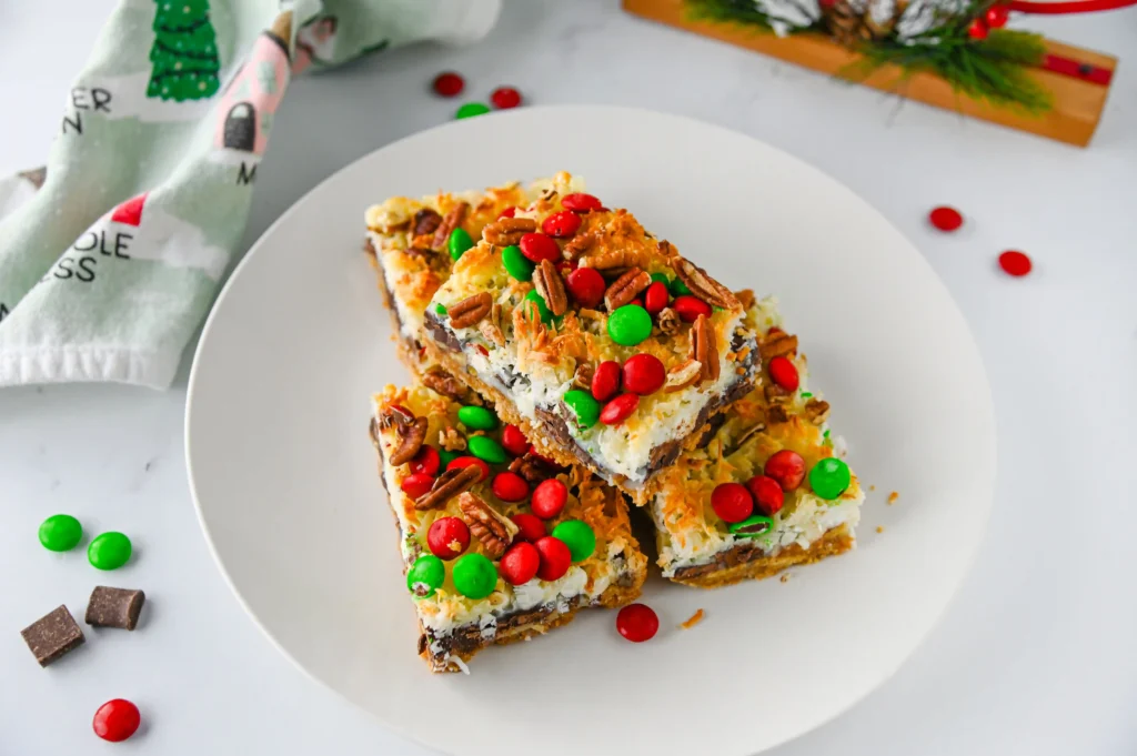 Christmas 7 Layer Bars with green and red m&ms on top on a white plate