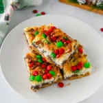 Christmas 7 Layer Bars with green and red m&ms on top on a white plate