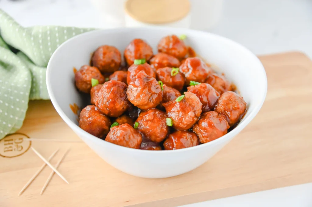 Cranberry Meatballs in a white bowl on a wooden board
