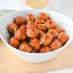 Cranberry Meatballs in a white bowl on a wooden board