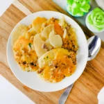 Hamburger Potato Casserole on a white plate resting on a wooden board with a spoon