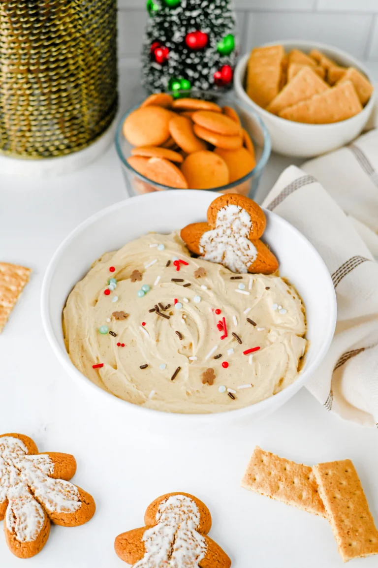Gingerbread dip with sprinkles in a white bowl with a gingerbread cookie in it