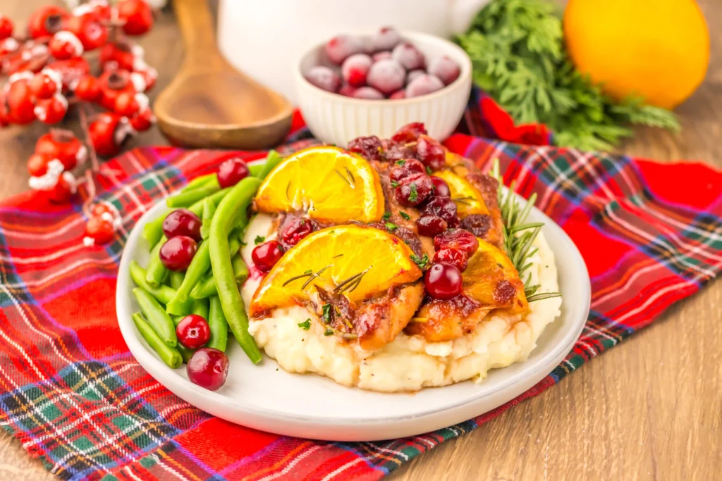 baked Christmas chicken with cranberries and lemon slices on a plate with green beans