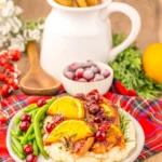 baked Christmas chicken with cranberries and lemon slices on a plate with green beans