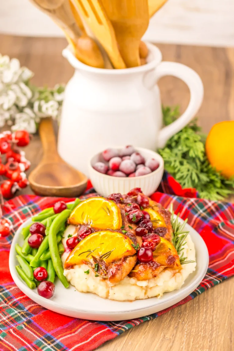 baked Christmas chicken with cranberries and lemon slices on a plate with green beans