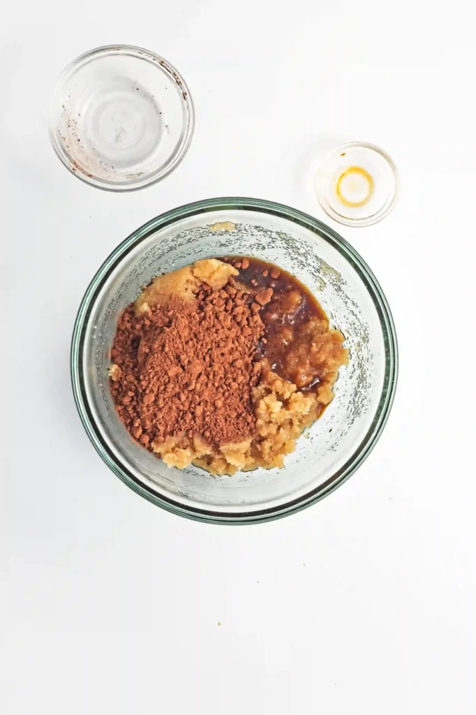 cocoa powder, oil, and sugars in a glass mixing bowl