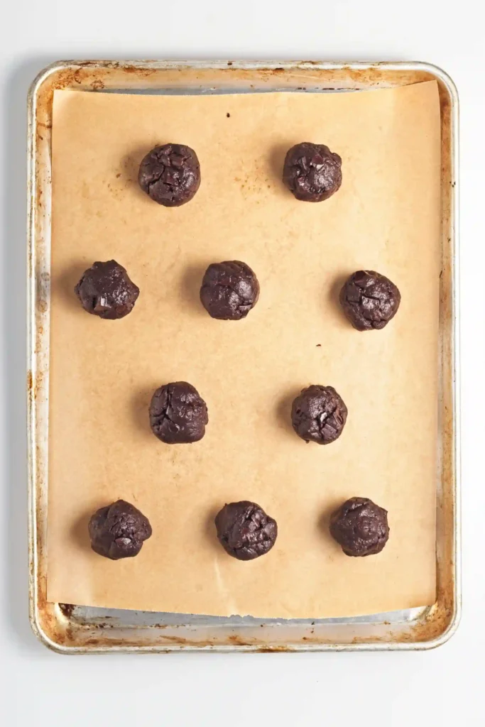 unbaked chocolate cookie batter on a baking sheet lined with parchment paper