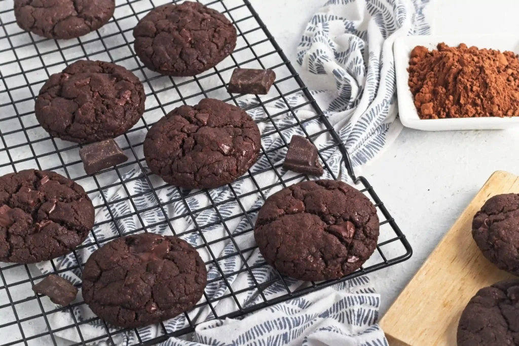 Double Chocolate Cookies with chocolate chips on a black cooling rack