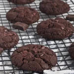 Double Chocolate Cookies with chocolate chips on a black cooling rack