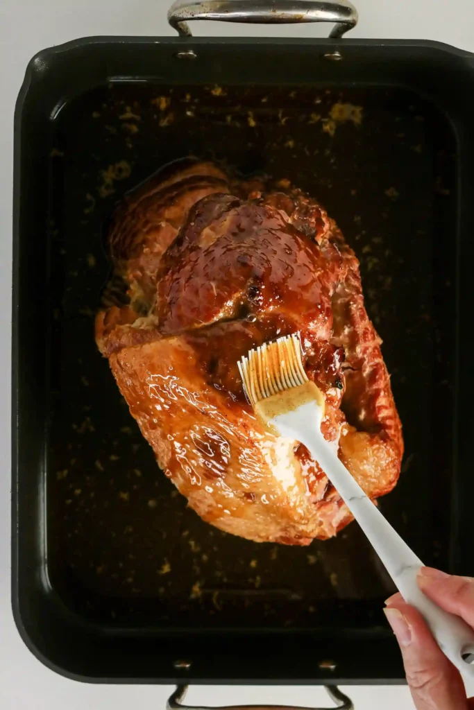 a ham being brushed with a honey ham