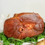 a ham with a honey glaze on a plate with lettuce
