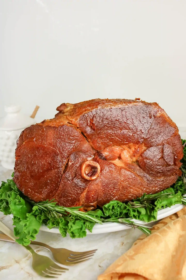 a ham with a honey glaze on a plate with lettuce