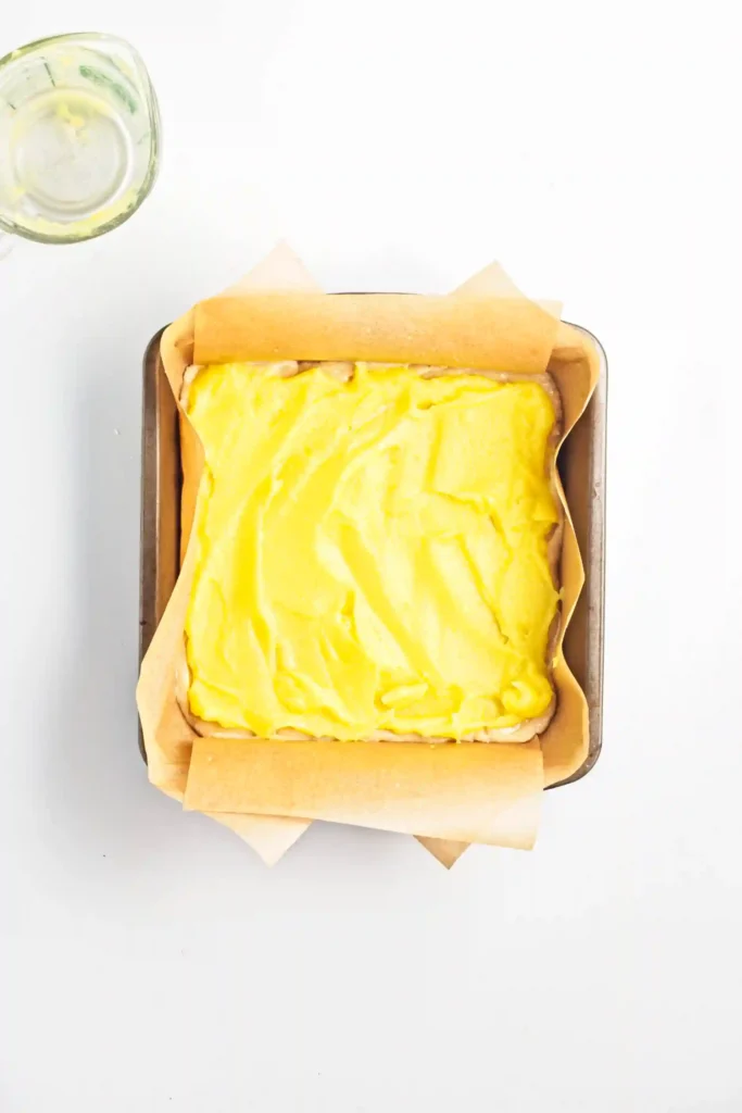 a square baking pan with unbaked lemon curd bars