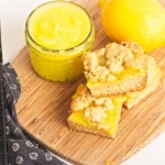 Lemon Curd Cookie Bars on a wooden board next to a jar of lemon curd