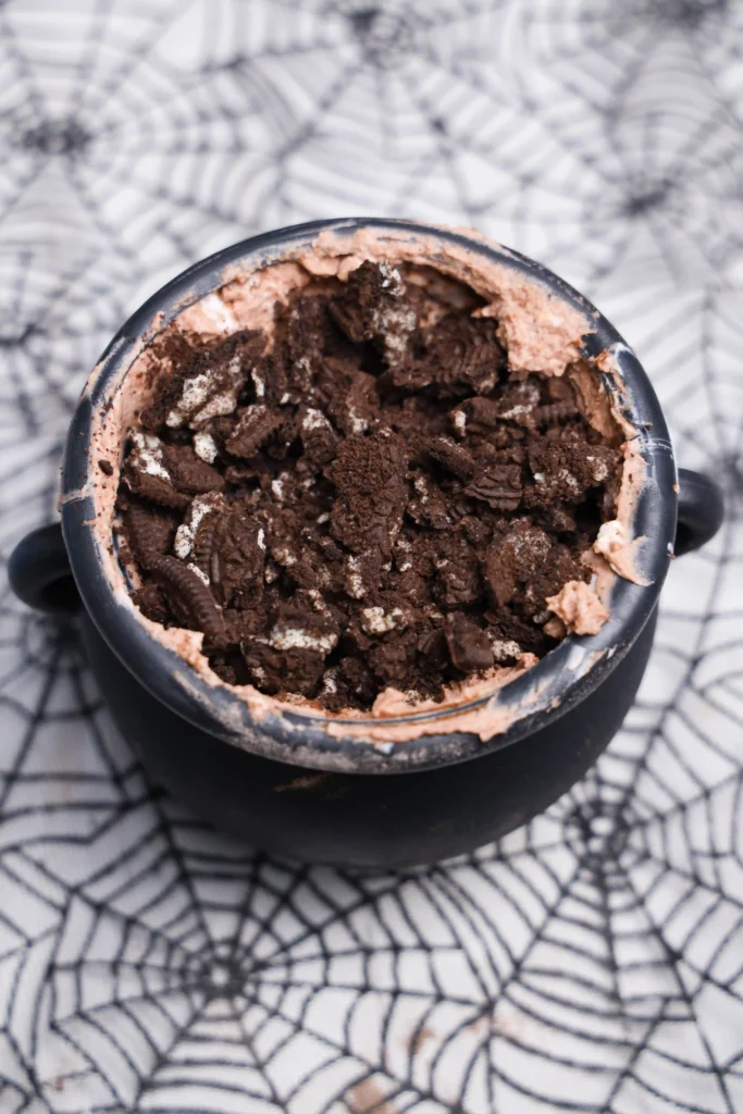 dirt cups in cauldrons with crushed Oreos on top