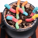 Halloween Dirt Cups in a cauldron and toped with gummy worms