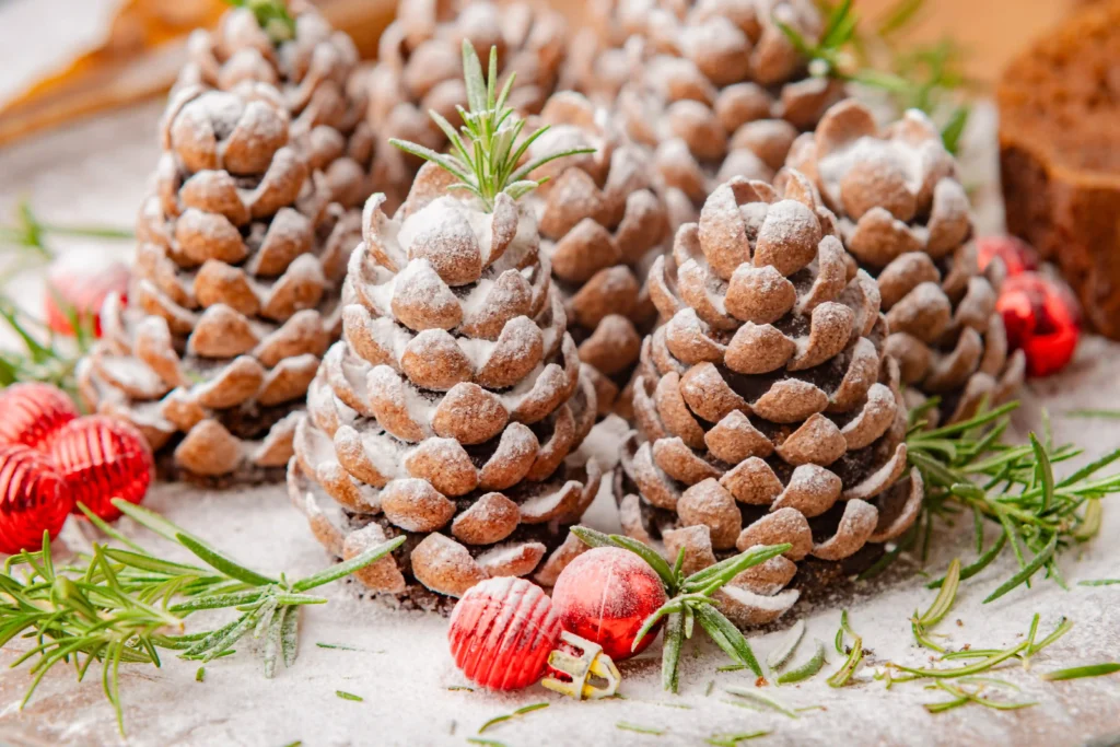 pinecone truffles with powdered sugar on top and sprigs of herbs and ornaments around