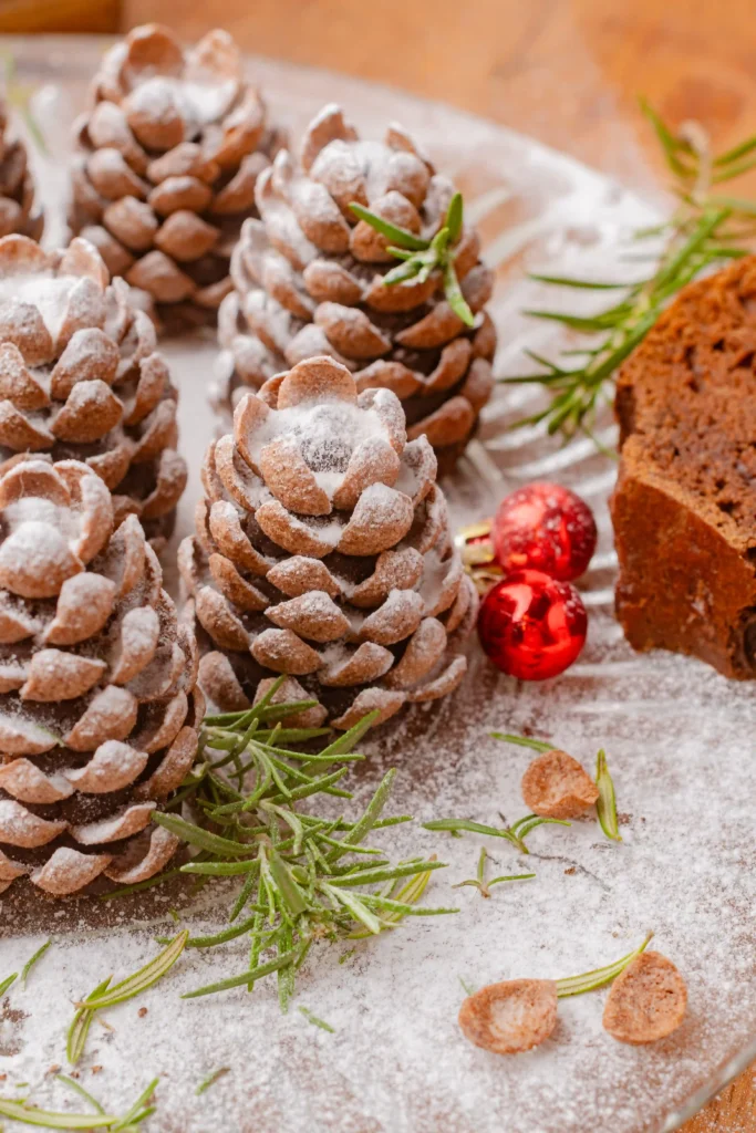 pinecone truffles with powdered sugar on top and sprigs of herbs and ornaments around