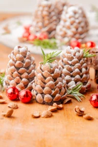 pinecone truffles with powdered sugar on top and sprigs of herbs and ornaments around