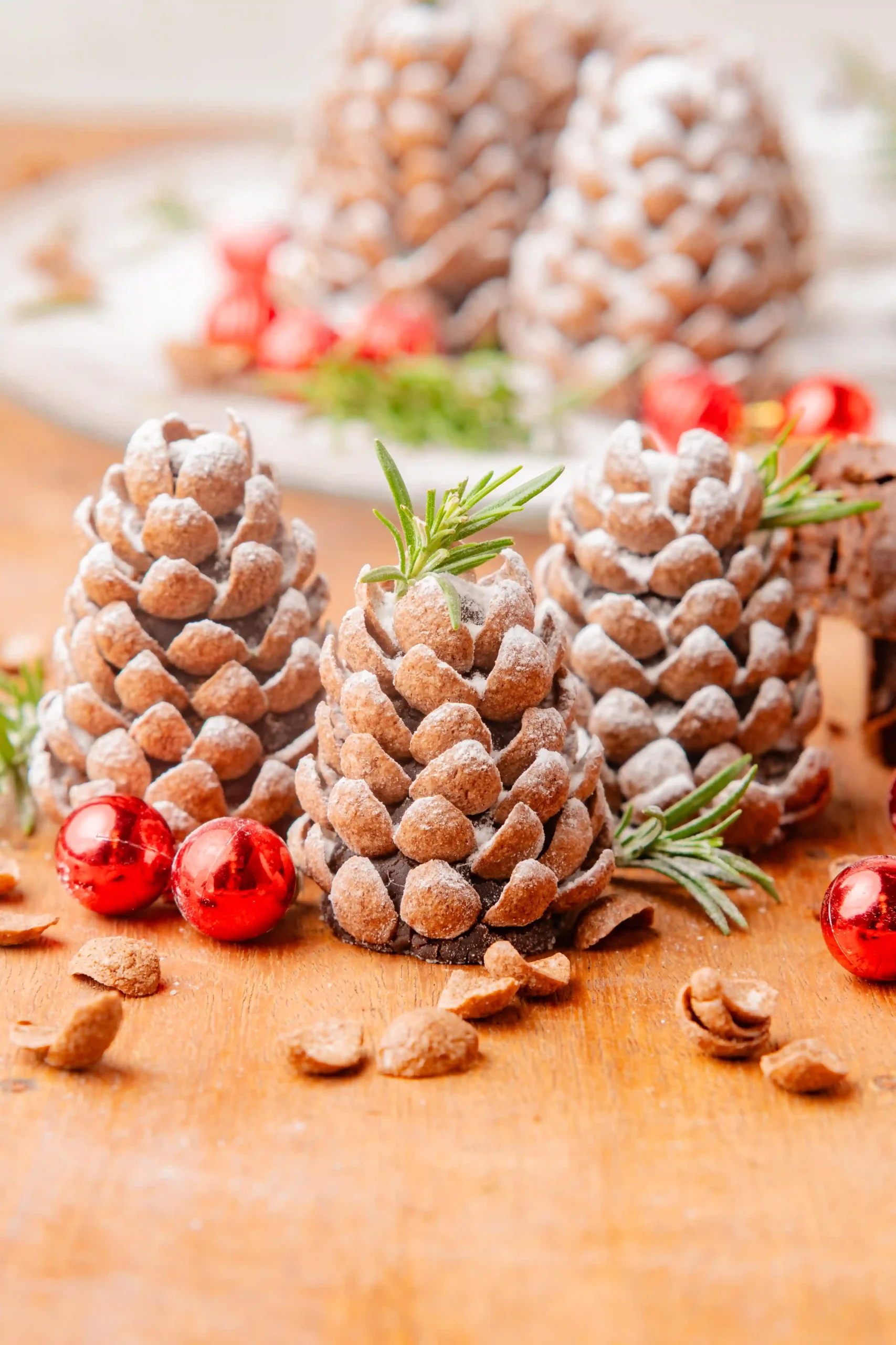 pinecone truffles with powdered sugar on top and sprigs of herbs and ornaments around