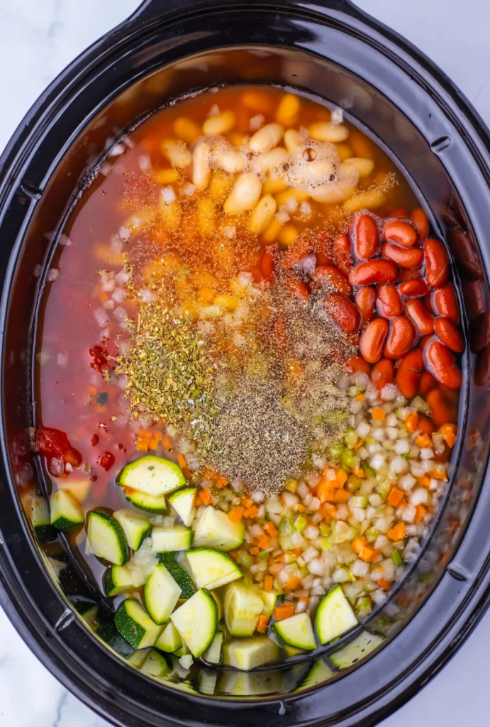 chicken, veggies, broth, spices, and beans in a slow cooker