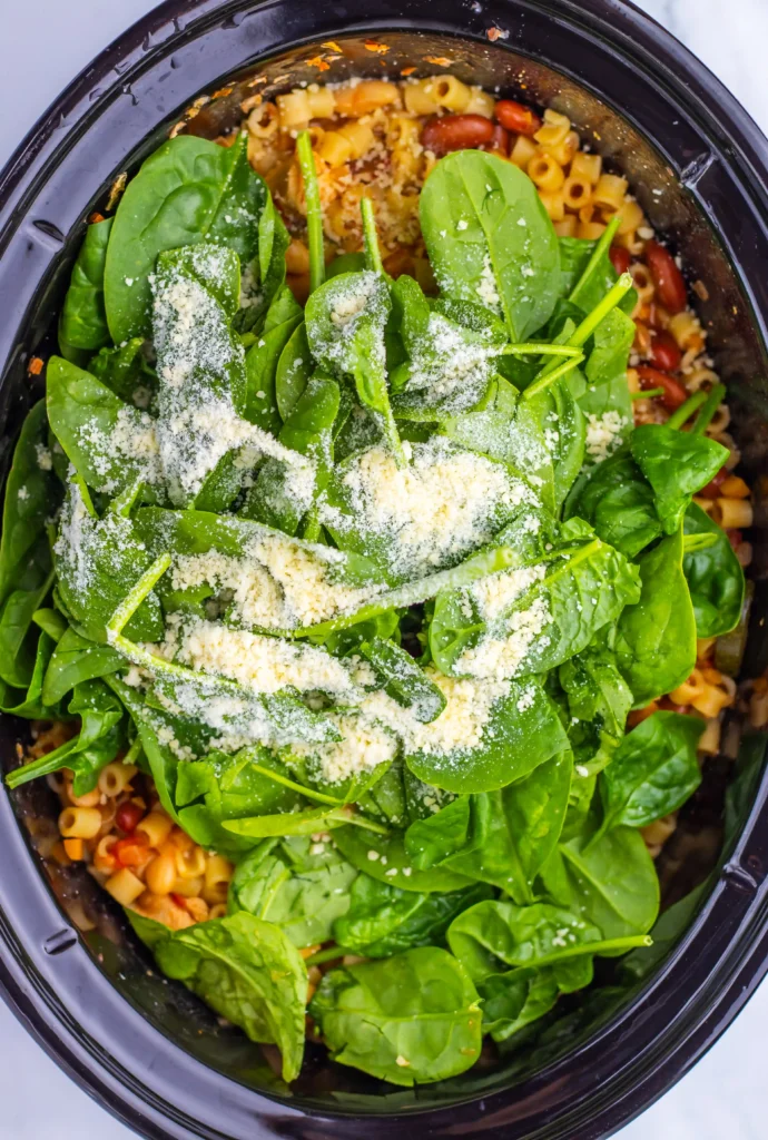 spinach and cheese in a crockpot of minestrone soup