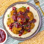 Turkey Stuffing Meatballs With Cranberry Glaze on a plate with mashed potatoes around the edge