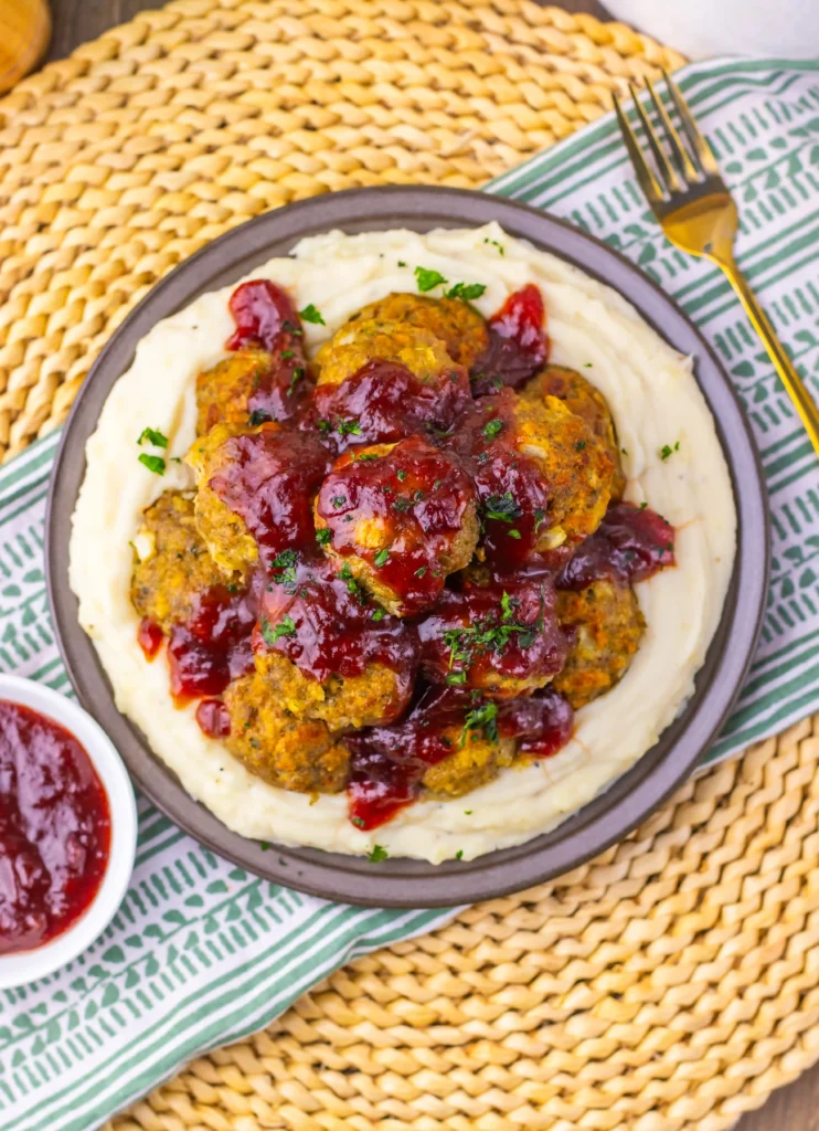 Turkey Stuffing Meatballs With Cranberry Glaze on a plate with mashed potatoes around the edge