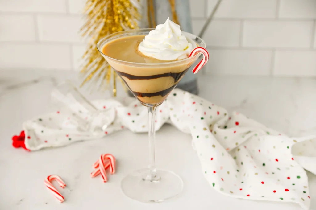 a Baileys Peppermint Martini with chocolate sauce around the glass and topped with whipped cream and a candy cane