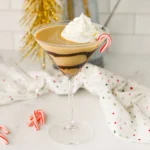 a Baileys Peppermint Martini with chocolate sauce around the glass and topped with whipped cream and a candy cane