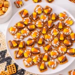 pretzels with chocolate and candy corn on top on a white plate