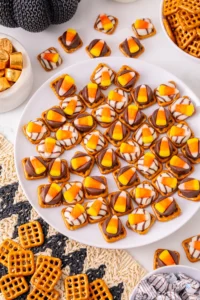 pretzels with chocolate and candy corn on top on a white plate