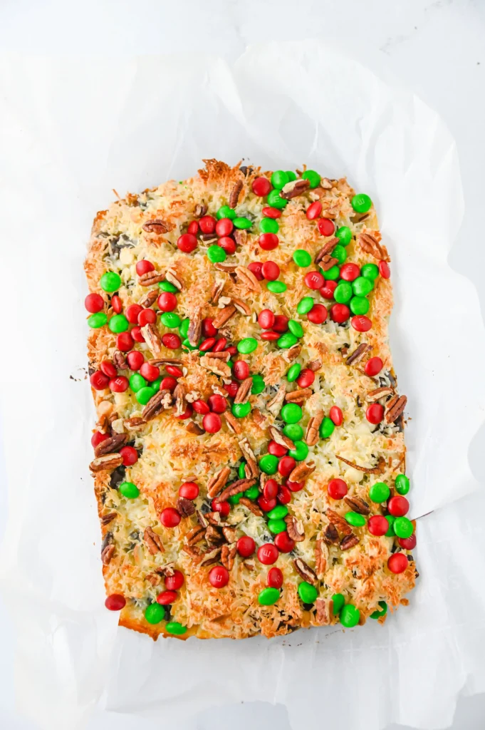 Christmas 7 Layer Bars with green and red m&ms on top on a baking sheet with parchment