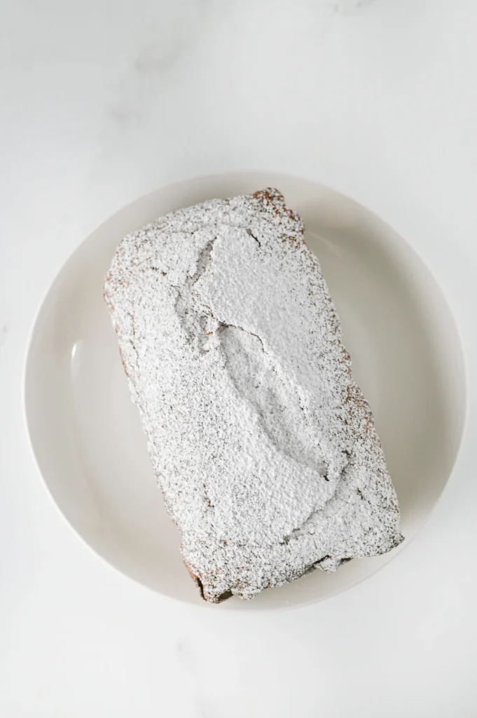 a gingerbread loaf on a plate with powdered sugar dusted on top