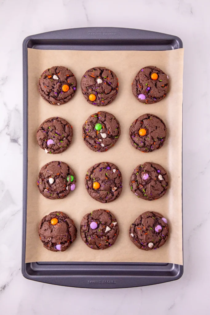 chocolate cookies with halloween sprinkles on a baking tray with parchment paper