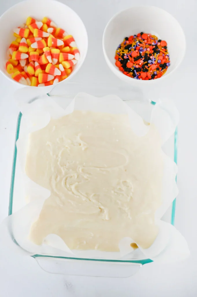 sweetened condensed milk and white chocolate chips melted in a baking dish with parchment