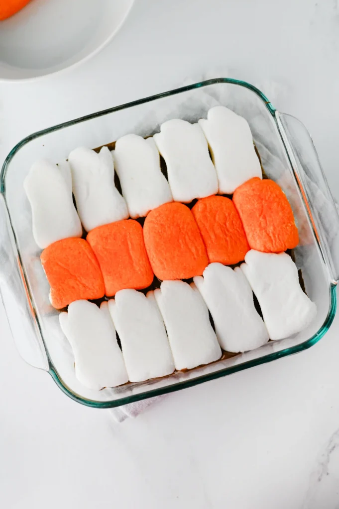 a glass pan with melted chocolate and Halloween peeps on top