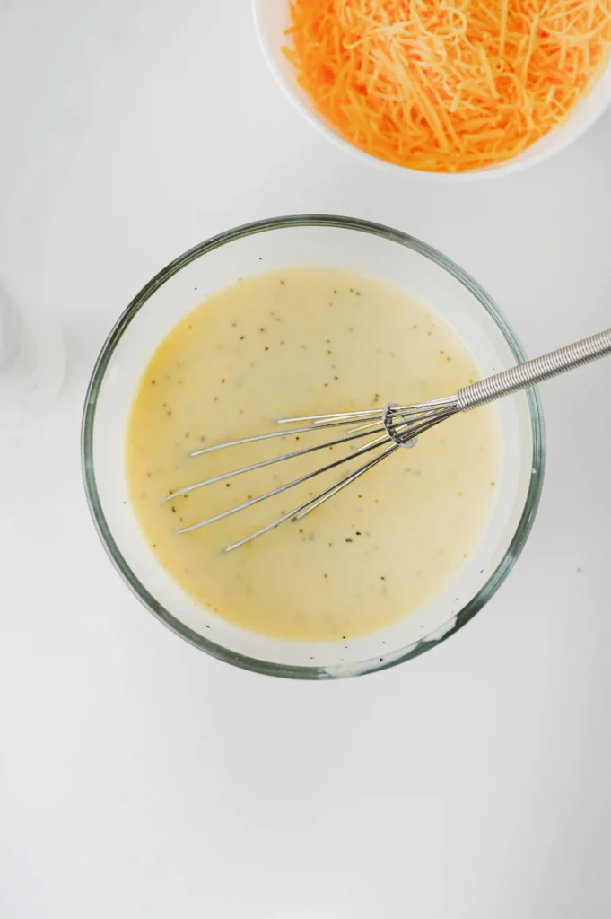cream of chicken soup, milk, salt and pepper in a glass bowl with a mixing bowl