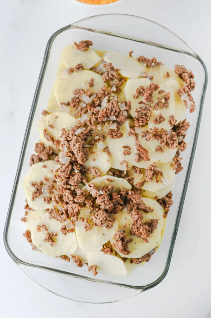 potatoes in a glass pan with cream of chicken soup and beef