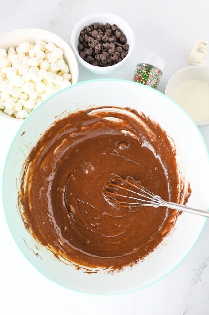 unbaked brownie batter in a bowl with a whisk