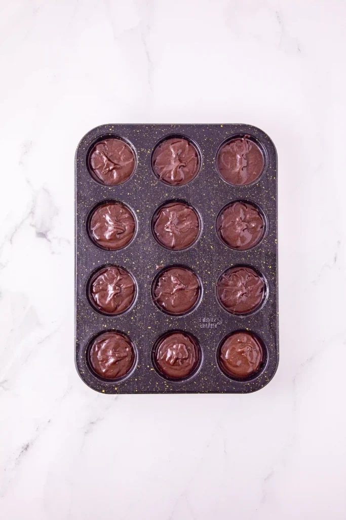 muffin tin with unbaked brownie mix in it