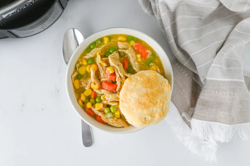 Crock Pot Chicken Pot Pie soup in a bowl with a biscuit