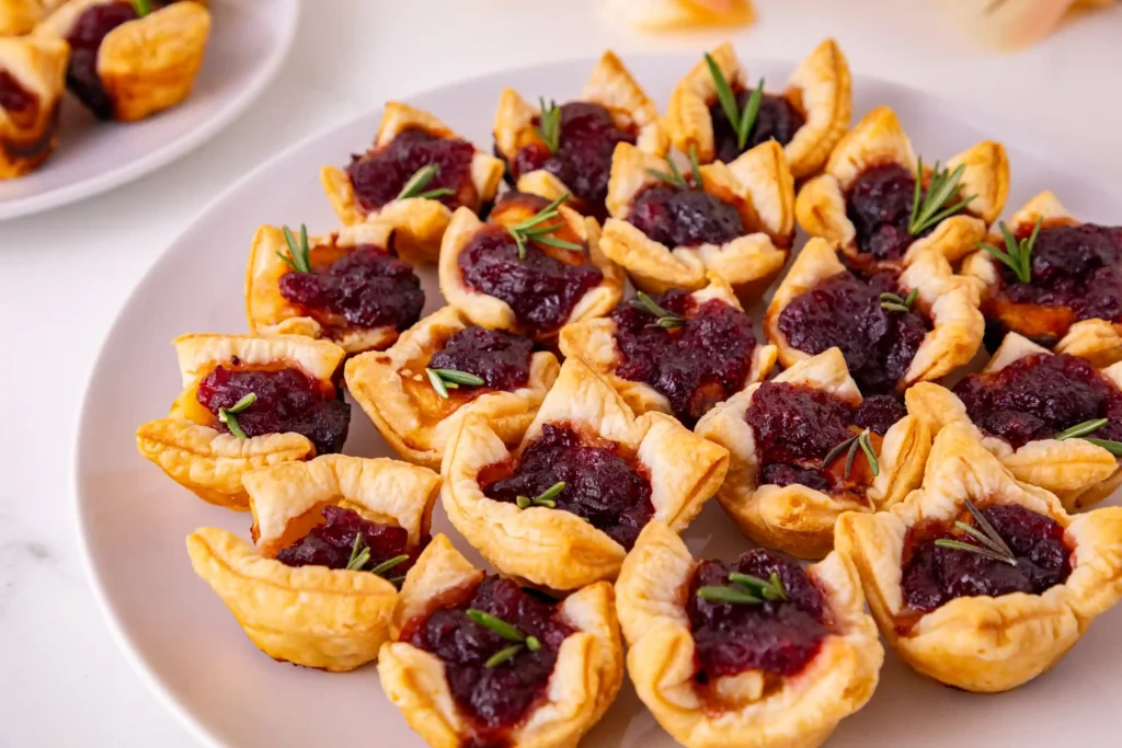 puff pastry squares with cranberry sauce and brie cheese on a white plate